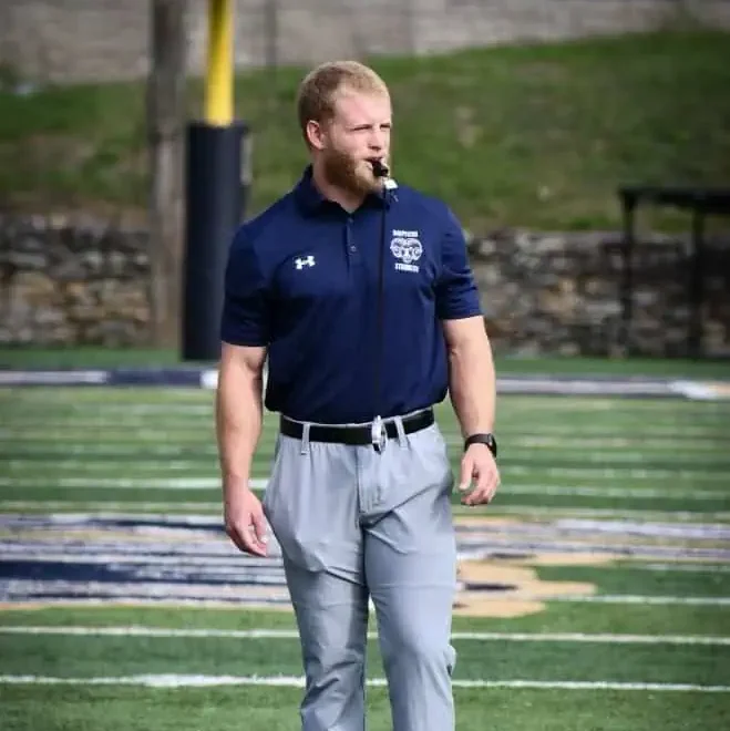 Coach of Peak Performance leading workout on football field with whistle